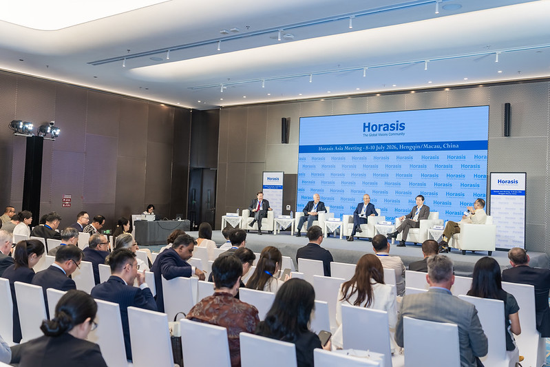 A panel session on stage at Horasis Asia Meeting 2026 in Hengqin/Macau, China, with delegates seated in the audience between conversations